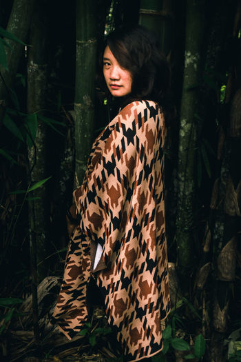 Young woman standing against plants
