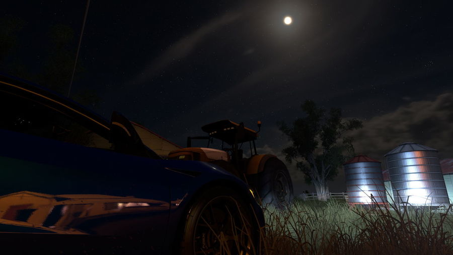 Cars on illuminated field against sky at night