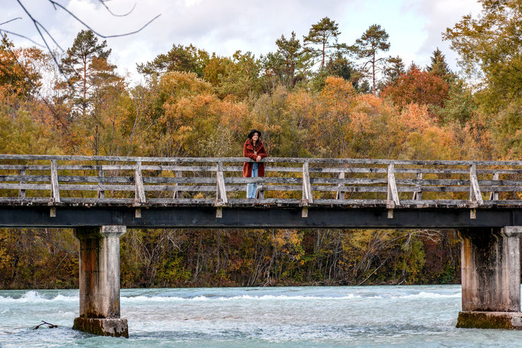Woman standing on footbridge above river. autumn, fall, nature.
