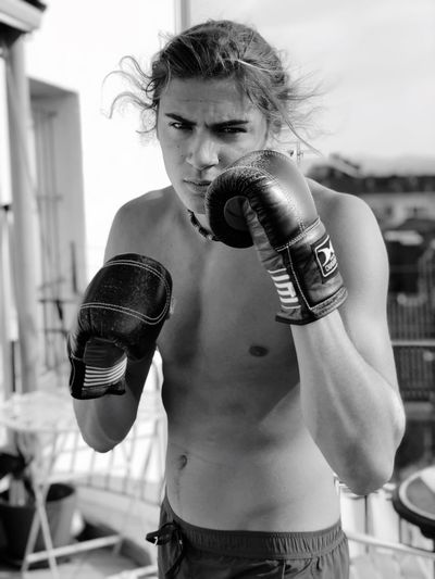 Portrait of shirtless young man wearing boxing gloves