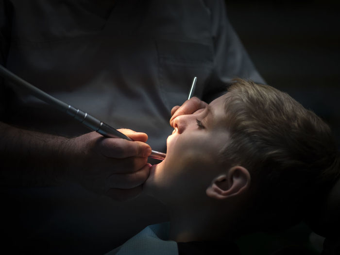 Midsection of male dentist examining boy at hospital