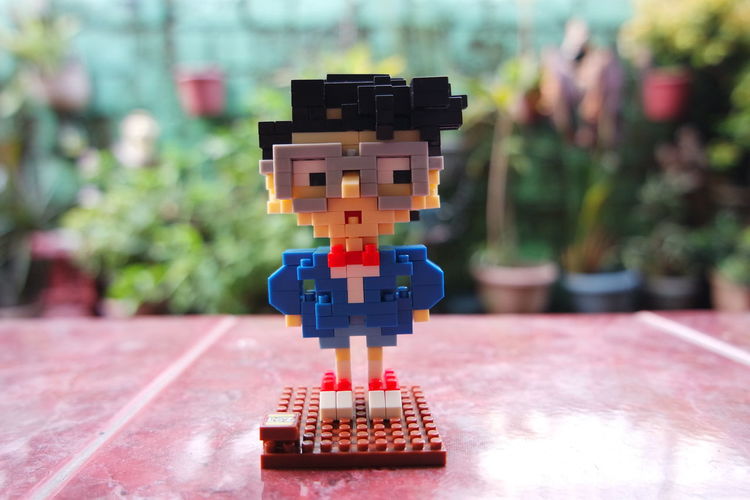 Close-up of man made with toy blocks on tile