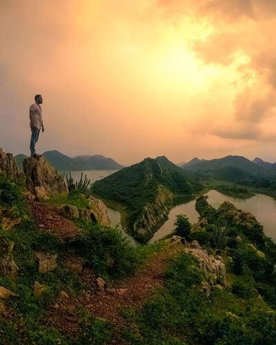 Man looking at mountains against sky during sunset