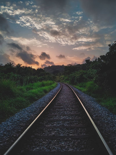 Surface level of railroad track against sky during sunset