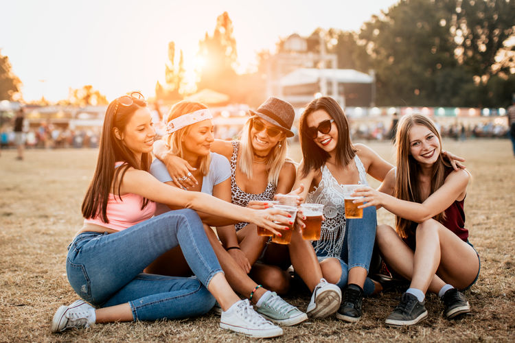 Group of female friends drinking beer and having fun at music festival
