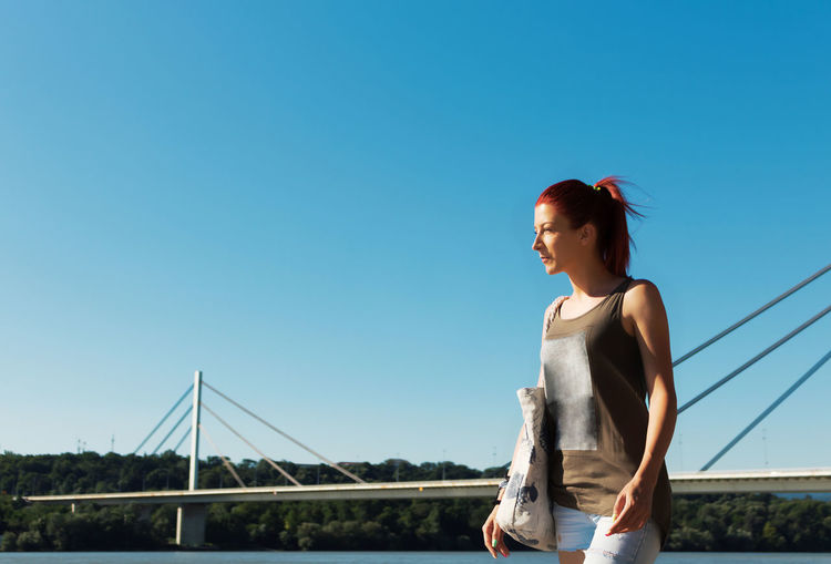 Beautiful woman enjoying in summer day by the river against the sky. copy space.