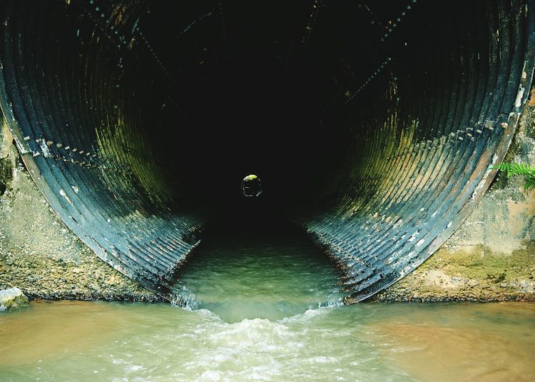 Water flowing through tunnel under bridge