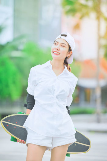Happy young woman standing against blurred background