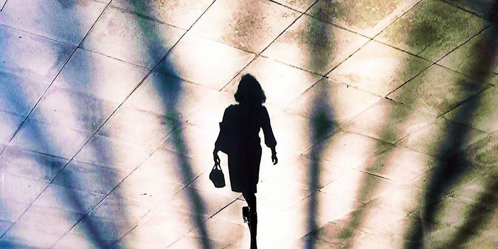 Rear view of silhouette woman walking on tiled floor