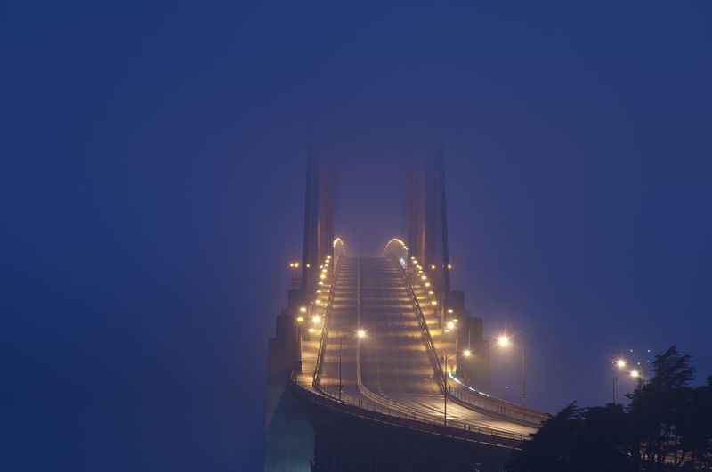 Illuminated suspension bridge against sky at night