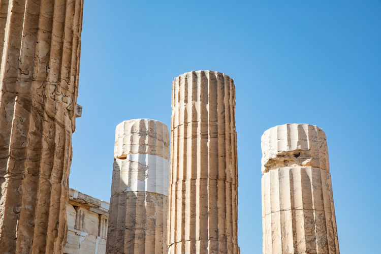 Low angle view of old columns against clear blue sky