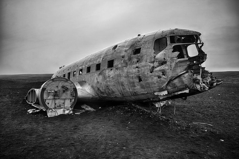 Plane wreck on black beach against sky