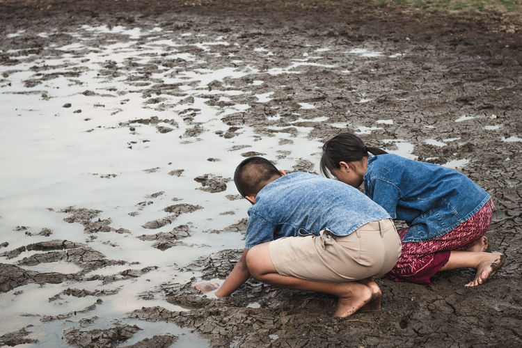 Siblings playing at muddy lakeshore