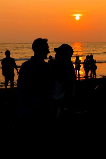 Silhouette people at beach during sunset