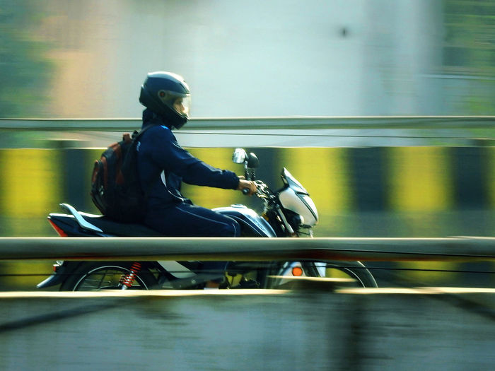 Side view of man riding motorcycle on bridge