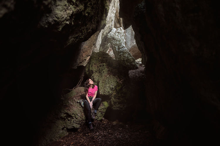 Woman standing on rock formation in cave