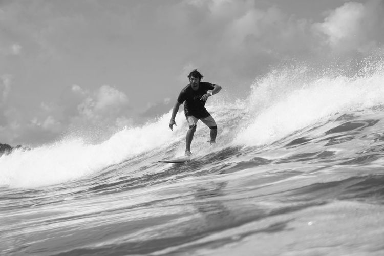 Full length of man surfing in sea against sky