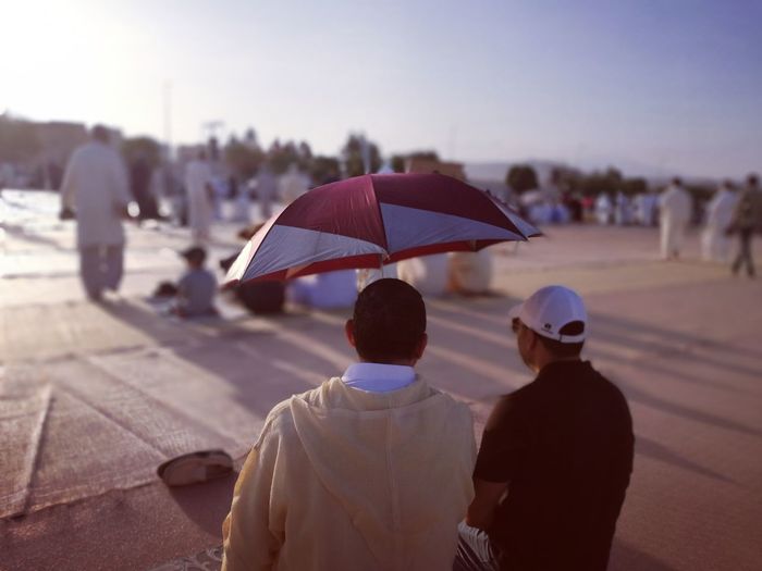Rear view of men sitting with umbrella in city
