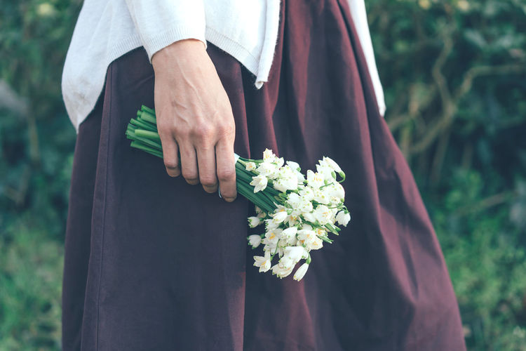 Closeup of female hand holding a bouquet of snowdrops in nature