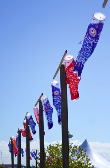 Low angle view of flags hanging against clear blue sky