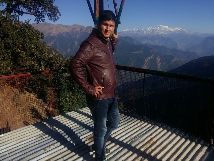 Man standing on railing against mountain range