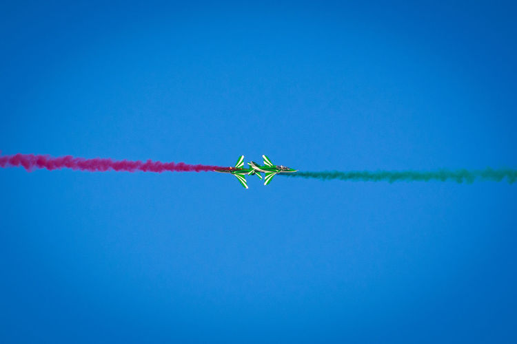 Low angle view of airshow against clear blue sky