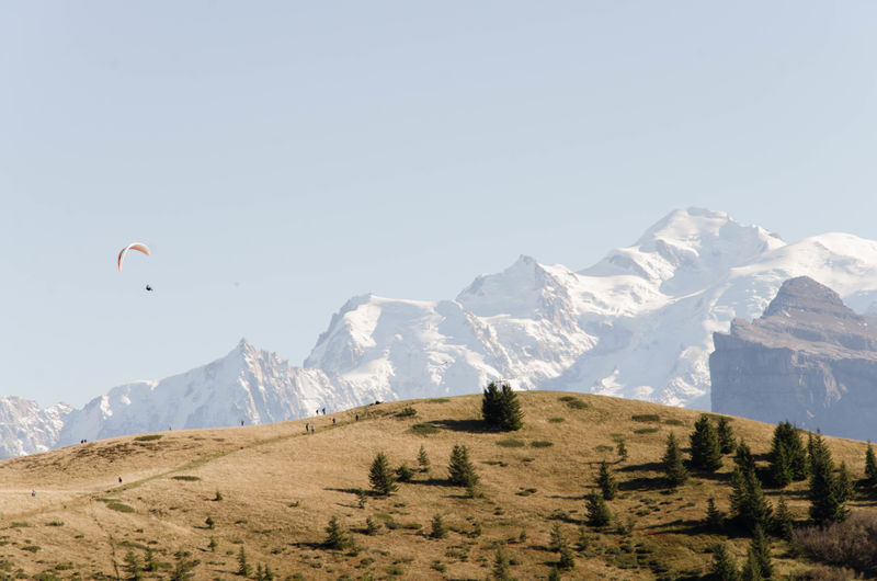 Verchaix, france, alps, hiking trail. snow capped mountains with paragliders in blue sky
