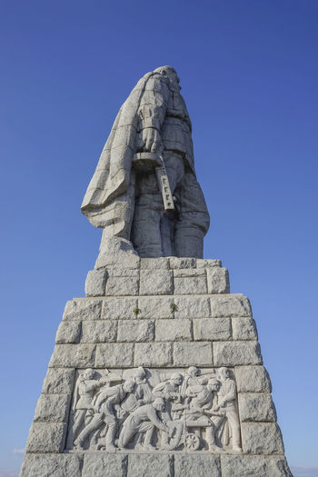 Low angle view of a russian red army monument with a stone statue of the unknown soldier.