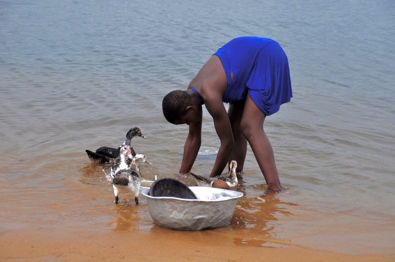 Woman washing kitchen utensil in lake