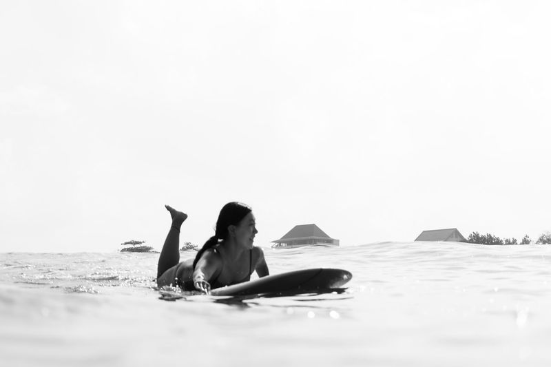 Rear view of woman swimming in sea against clear sky