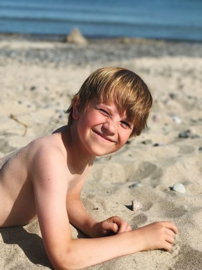 Portrait of shirtless boy on sand at beach