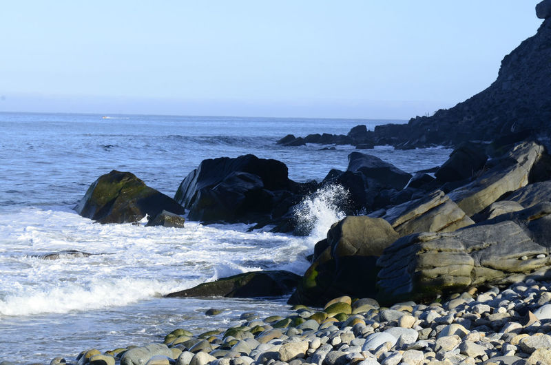 Motion of pacific ocean wave splashing against shoreline rock in baja california sur, mexico