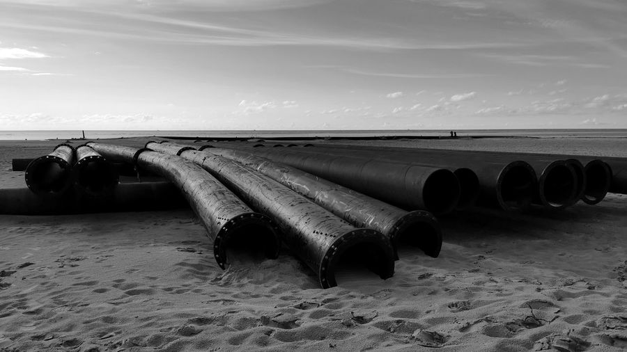 Deck chairs on beach against sky