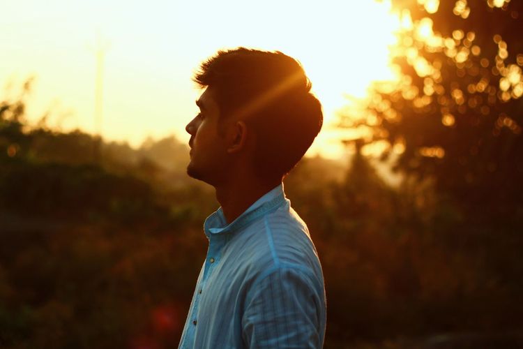 Young man standing against sky during sunset