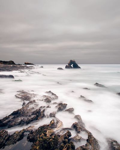 Dramatic view of rocks in sea against sky