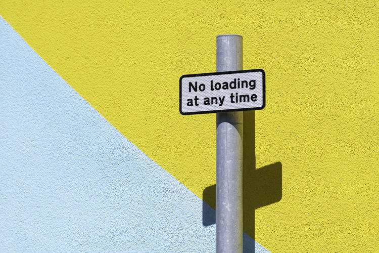 Close-up of no loading information sign on wall