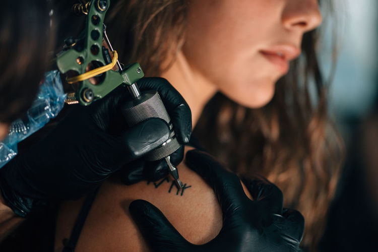 Close-up of mam making tattoo on woman hand