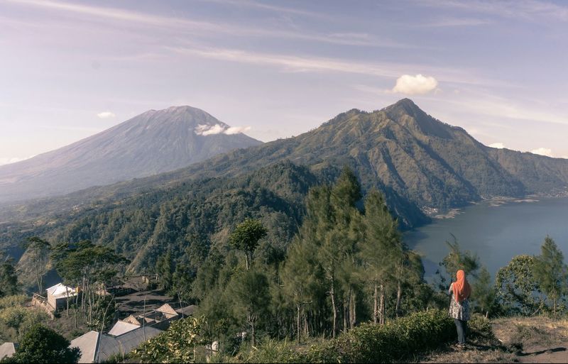 Rear view of woman standing on mountain against sky