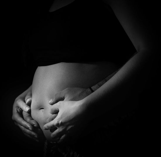 Close-up of a pregnant woman against black background