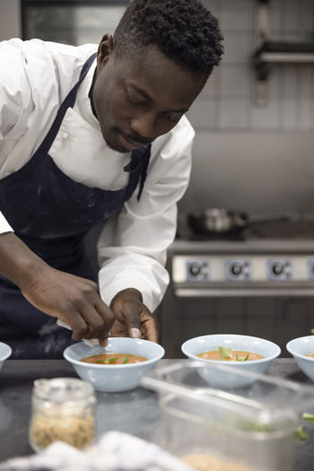 Male chef wiping bowl of soup while working at restaurant