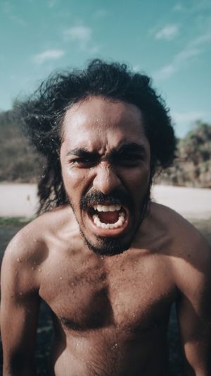 Close-up portrait of shirtless man screaming outdoors
