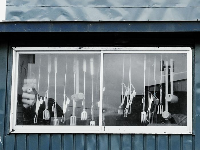 Gardening forks and sledgehammers seen through workshop window