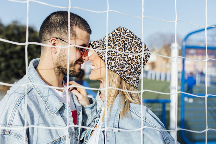 Girlfriend and boyfriend in the fence looking each other and touching noses. happy couple.