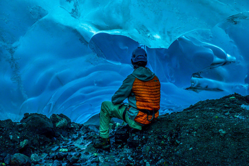 Rear view of man sitting in frozen cave