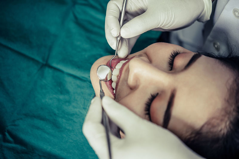 Close-up of young woman getting her teeth examined by dentist