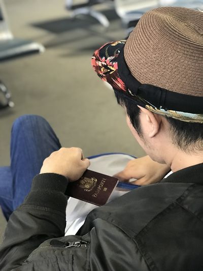 High angle view of man holding passport while sitting at airport