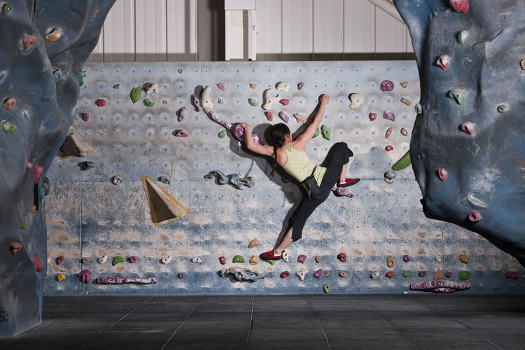 Mature woman practising at indoor climbing wall in the uk