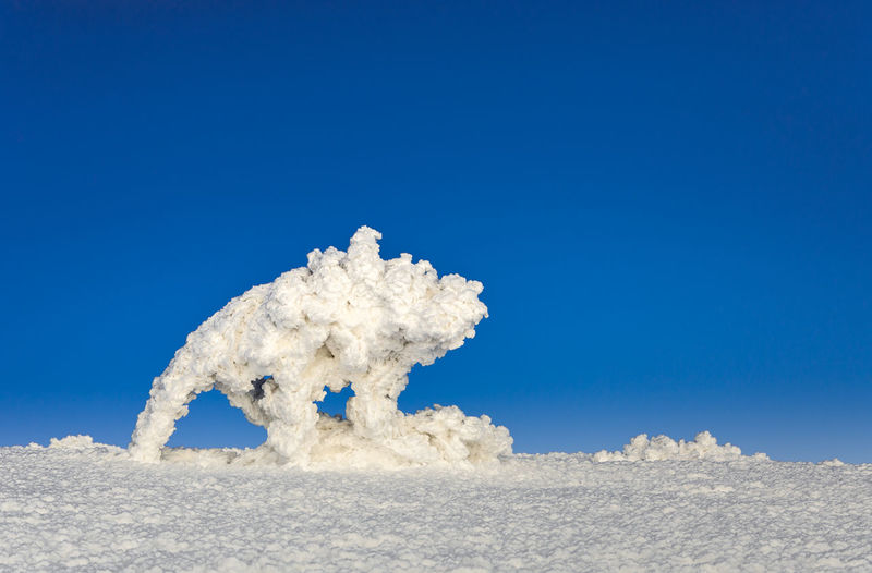 Snow covered sculpture against clear blue sky