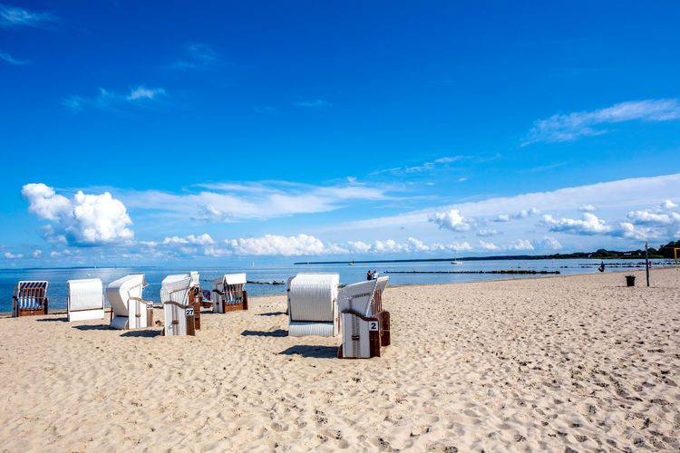 Hooded chairs on beach against blue sky