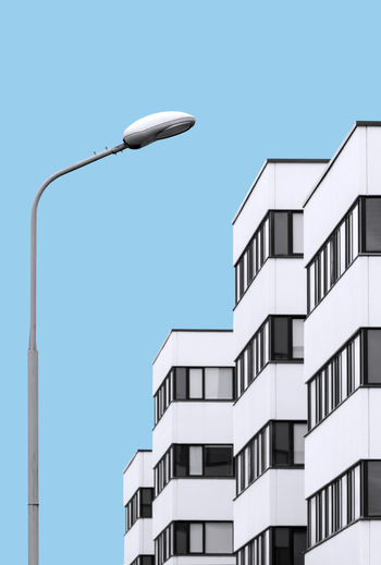 Low angle view of street light by buildings against clear sky